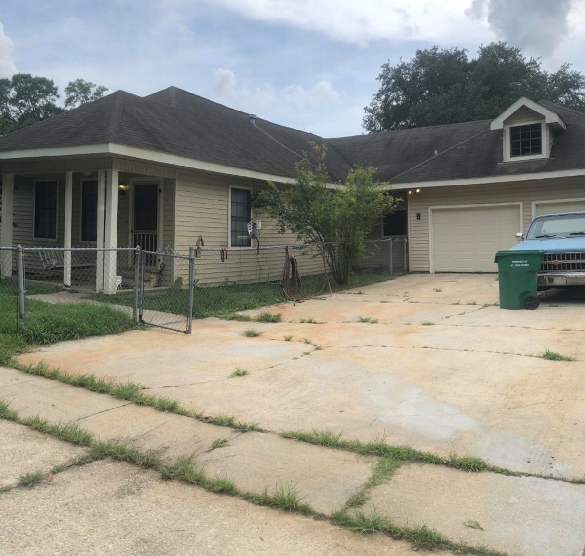 Before: a house with overgrown grass along the fence and weeds growing through the driveway cracks